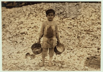 Manuel, 5 ans, migrant cueilleur de crevettes devant un tas de coquilles d