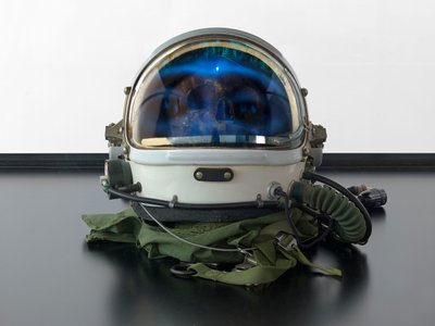 Alpha Omega, 2016 (verre, écran LCD, lecteur multimédia, réplique de crâne, casque spatial, bois) - Mat Collishaw