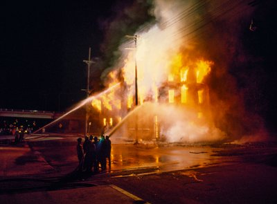Un bâtiment urbain complètement englouti par le feu et les flammes la nuit à Kansas City avec des pompiers - Ted Spiegel