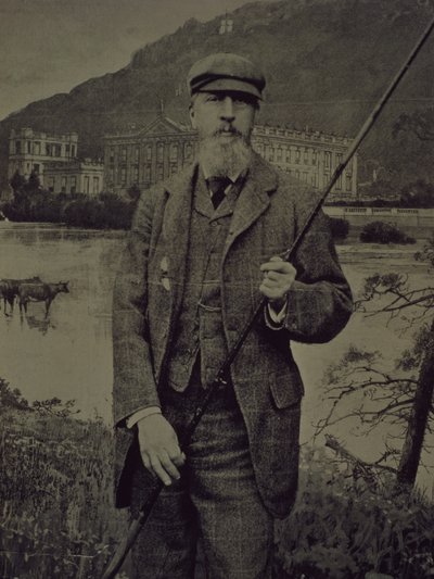 Portrait en studio du 8e duc de Devonshire en tweed tenant une canne à pêche devant un écran imprimé représentant Chatsworth - William M. Timlin