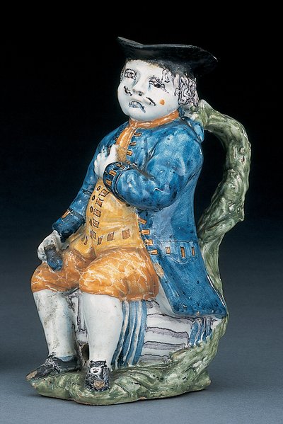 Cruche Toby avec visage et mains en manganèse pâle, tenant une cruche globulaire vide de couleur buff dans une veste et un pantalon bleu lavé, et un gilet vert, vers 1800 - Unbekannt