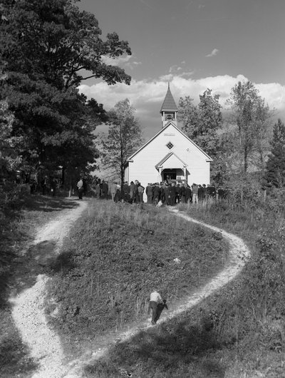Hommes rassemblés devant un petit bâtiment rural, une école ou une église avec cloche - Volkmar Wentzel