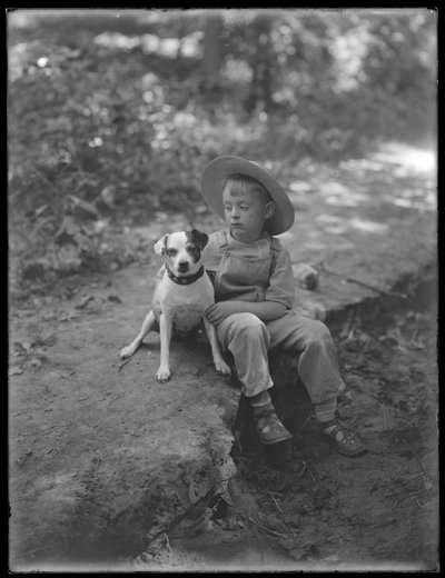 William Gray Hassler en chapeau de paille et salopette, posé assis dans les bois avec un petit chien (Bessie), 20 août 1911 - William Davis Hassler