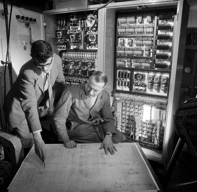 Ingénieurs discutant des plans devant le panneau de contrôle électronique qu