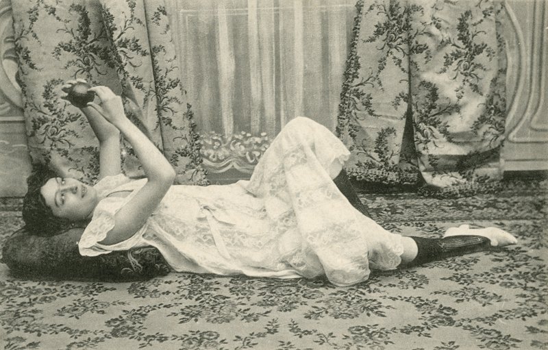 Fille, allongée sur le sol, tenant une balle au-dessus de sa tête - French Photographer