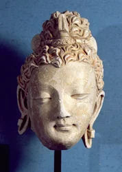 Tête de Bouddha souriant, style gréco-bouddhiste, de Hadda, 1er-4e siècle