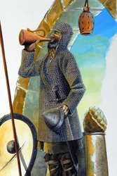 Première croisade : un chevalier au repos, équipé de son haubert, buvant à la carafe, son bouclier et sa lance sont placés près de lui.