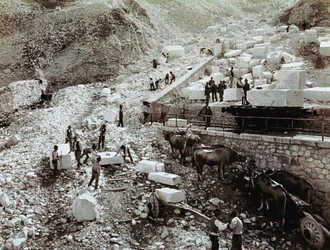 Gare avec des ouvriers chargeant des blocs de marbre sur des wagons de chemin de fer, trois paires de bœufs avec des wagons de transport sont visibles