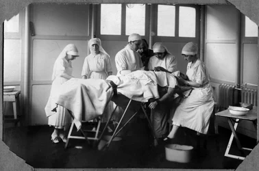 Première Guerre mondiale 1914-1918 : médecins et infirmières de la Croix-Rouge (Thérèse Pavillou ?) soignant un soldat endormi sous chloroforme dans le camp de Couville dans la Manche, Basse-Normandie, France. Photographie anonyme.