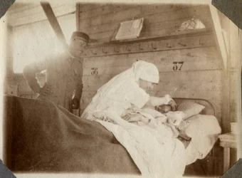 Première Guerre mondiale 1914-1918 : infirmière en blouse rasant un soldat (blessé de guerre français allongé dans un lit), à Couville, Manche, Basse-Normandie, France. Photographie anonyme juillet 1917. Collection privée, Stella.