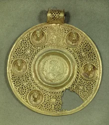 Médaillon circulaire en or : solidus de Constantin Ier le Grand (270-337 ap. J.-C.) frappé à Sirmium en 321 ap. J.-C., dans un cadre en opus interrasile, orné de 5 bustes en relief. 4e siècle ap. J.-C. Paris, Musée du Louvre