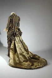 Robe de soirée, vers 1884 (vue oblique arrière). Satin de soie et velours coupé, dentelle, glands et franges en fil de soie. Charles Frederick Worth, France.