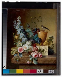 Un vase de fleurs sur un rebord de marbre et un panier de fleurs avec un chardonneret