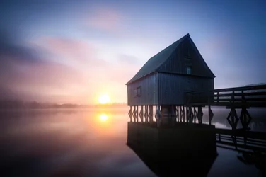 Lever de soleil sur le hangar à bateaux brumeux