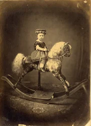Jeune fille assise sur un cheval à bascule tacheté