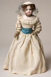 Poupée de mode en biscuit avec tête pivotante, portant une longue robe crème et un chapeau