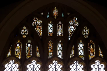 Fenêtre Ew représentant les lumières de la rosace avec Dieu, la Trinité, Saint Pierre, Saint Paul, Sainte Catherine et Gabriel; et un oiseau
