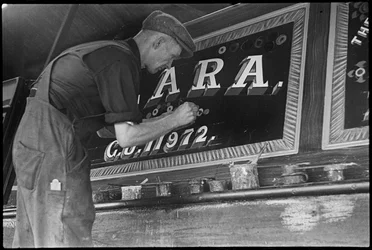 Frank Jones, en train de peindre le panneau des noms sur une péniche, 20e siècle (photo)
