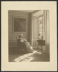 [Intérieur avec une femme assise en costume]