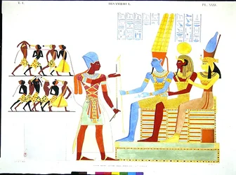 Un pharaon, en costume militaire, offre un groupe de prisonniers aux dieux Amon, Khonsu et Mout