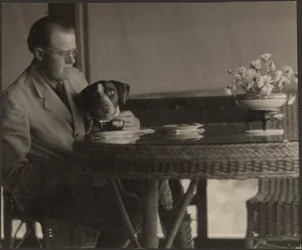 [Homme et chien assis à une table]