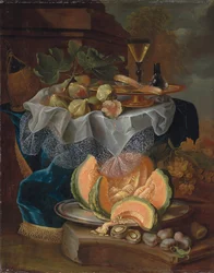Figues, une tazza dorée avec un verre à vin facon-de-venise, sur une table drapée, un melon coupé sur un plat en étain avec des prunes sur un socle