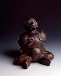 Art précolombien, civilisation maya, période initiale : vase anthropomorphe en argile représentant un homme assis, les mains sur la poitrine, portant un masque de singe à la bouche ouverte. Provenant d