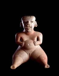 Art précolombien, civilisation maya, période préclassique : statuette en argile représentant une femme assise, le ventre gonflé et les jambes écartées (parturiente ?). Provenant de Kaminaljuyú, Guatemala. 19 x 25 cm. Guatemala, Museo Nacional de