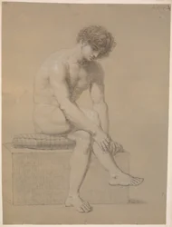 Modèle assis sur un bas piédestal avec coussin. Tourné vers la droite. Bras pendants. Jambes croisées