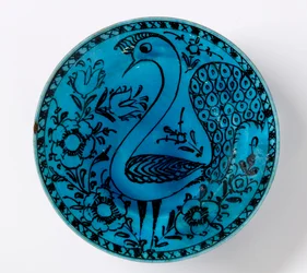 Un plat en céramique persane du XIXe siècle représentant un paon sur fond turquoise