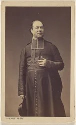 [ecclésiastique non identifié, debout, tenant un chapeau]
