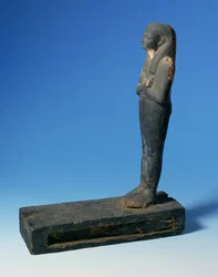 Figure de Ptah-Sokar-Osiris avec perruque tripartite et bras croisés sur un socle rectangulaire avec un compartiment contenant une section de papyrus, égyptien, 21e-22e Dynastie, c.900 av. J.-C. (bois)