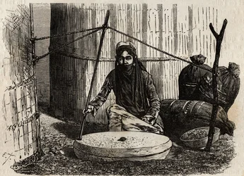 Femme turcomane utilisant la meule à grains, activant un ingénieux système de manivelle, la pierre supérieure tourne et en frottant cette pierre sur l