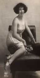 Jeune femme posant en jupon, assise dans un fauteuil