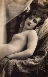 Une jeune femme nue posant sur un canapé