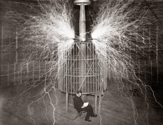 Nikola Tesla assis dans son laboratoire de Colorado Springs avec son « Transmetteur amplifiant »