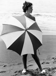 Femme avec un parasol sur la plage, vers 1960 (photo n/b)