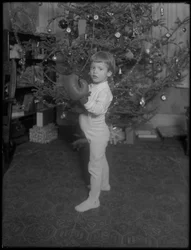 Enfant non identifié devant un sapin de Noël portant des gants de boxe, 1915-16